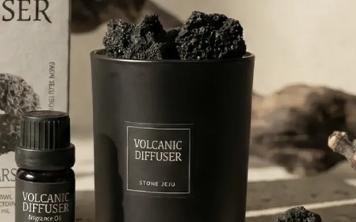 StoneJeju 火山石擴香 350：黑色玻璃器皿盛滿濟州火山石，旁邊是柑橘香氛油